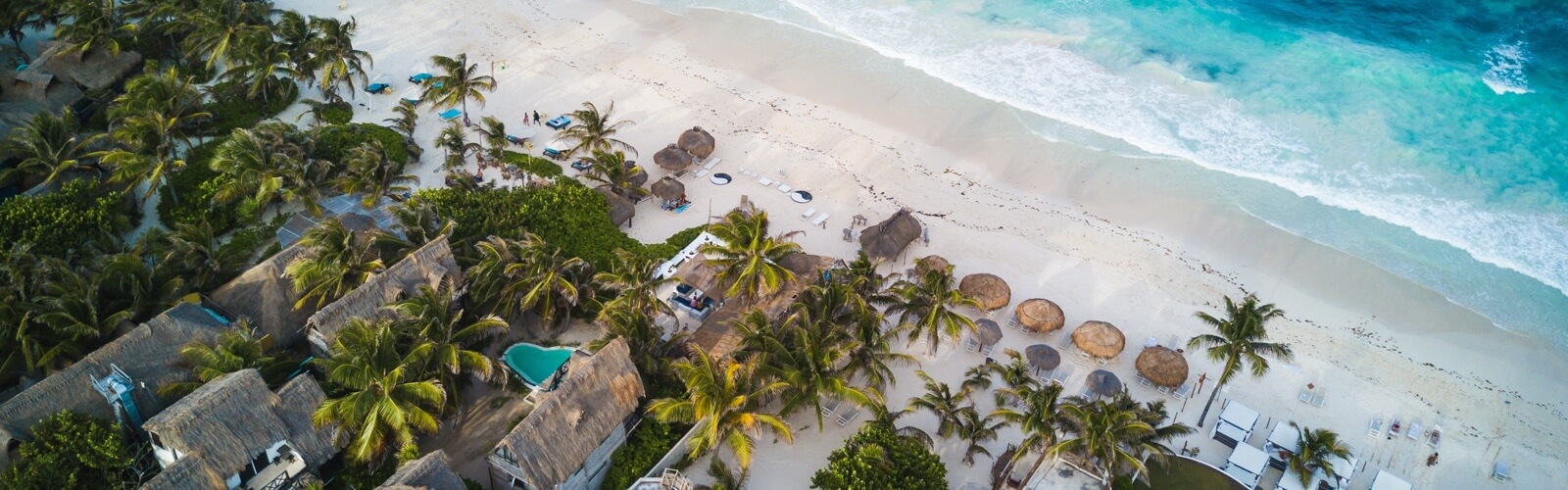 beach huts on white sandy beach with blue water