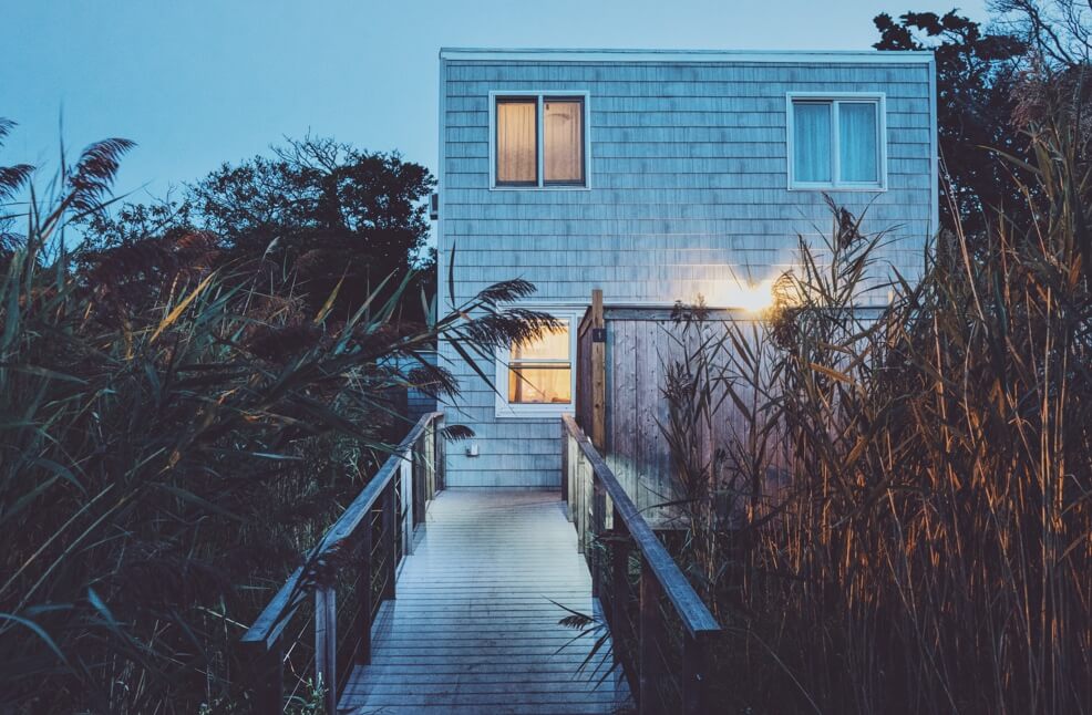 house surrounded by shrubs with wooden boardwalk